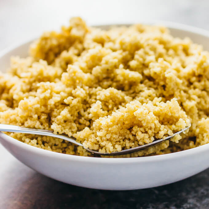 fluffing cooked couscous in white bowl