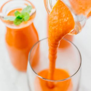 pouring carrot smoothie into a glass