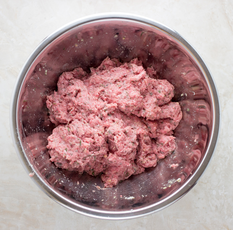 Raw meatball mixture in a stainless steel bowl