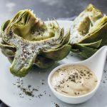 freshly cooked artichokes on white plate