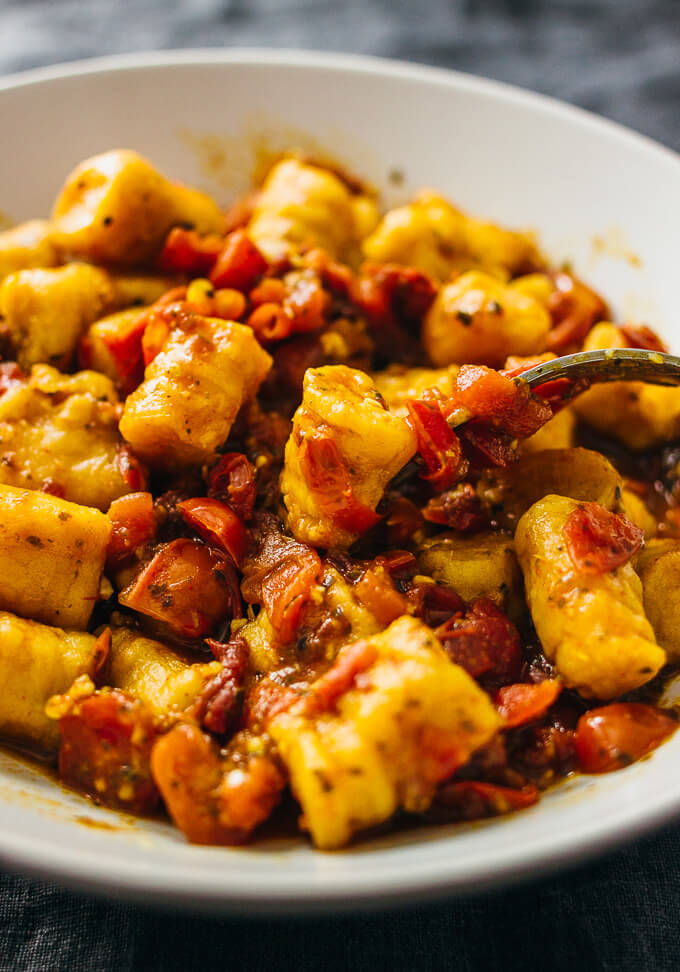 mixing sweet potato gnocchi with a spicy red sauce