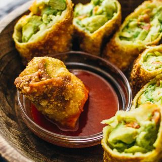dipping an avocado egg roll into sweet chili sauce