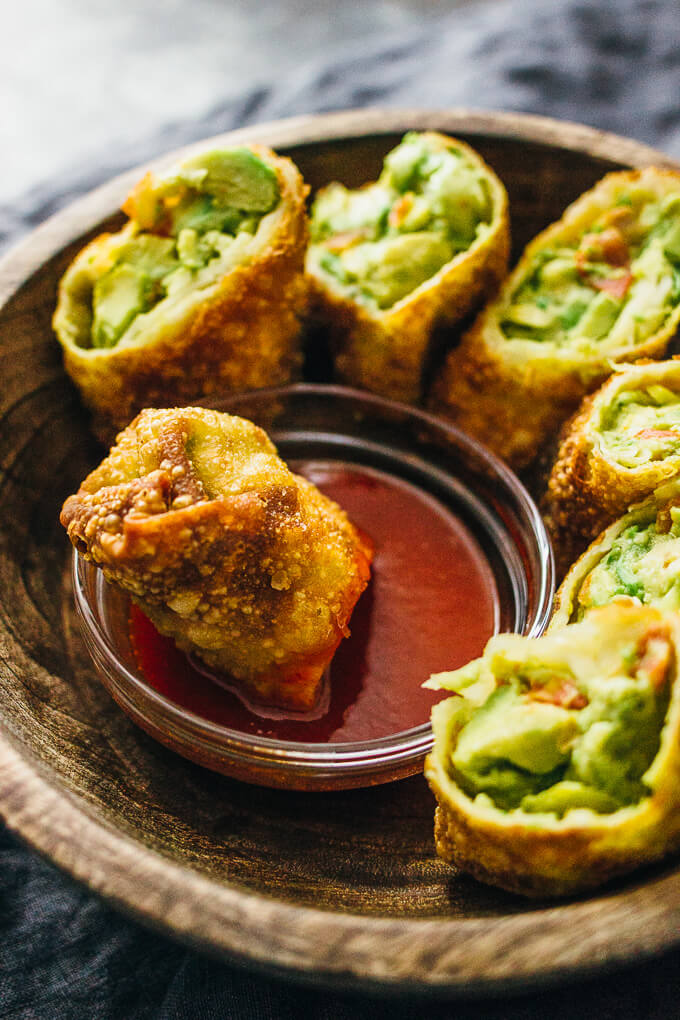 dipping an avocado egg roll into sweet chili sauce