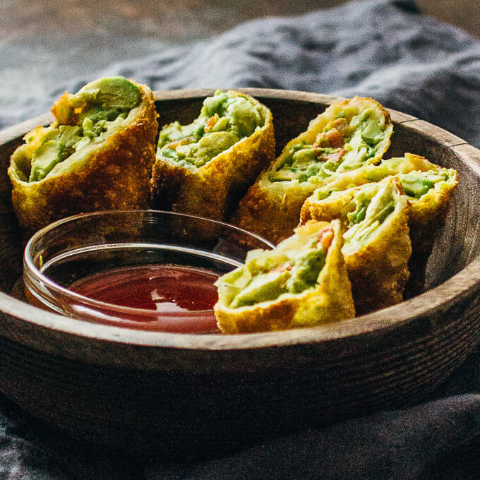 avocado egg rolls with sweet chili sauce in a wooden bowl