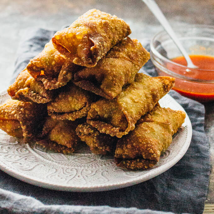 a stack of vegetable egg rolls with red sauce