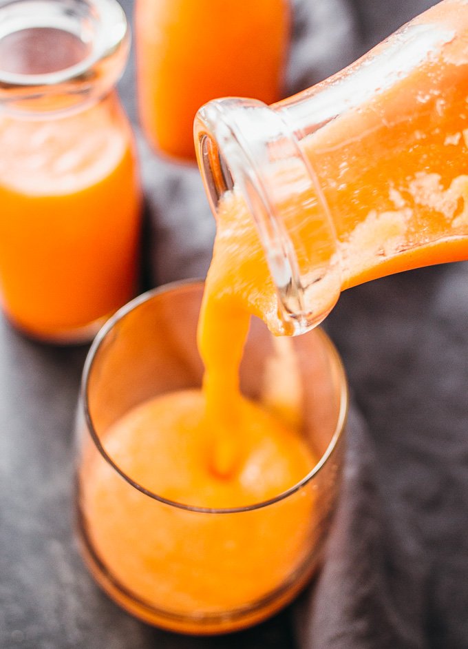 pouring pineapple smoothie into a glass