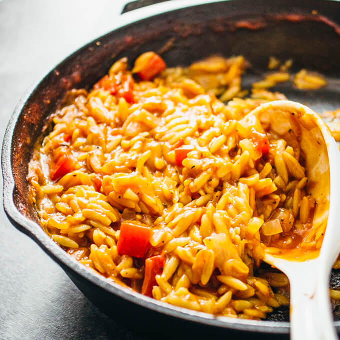scooping orzo pasta from skillet