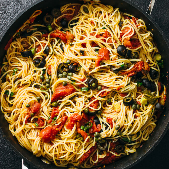 spaghetti puttanesca in a black pan