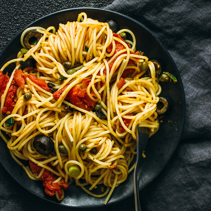 spaghetti puttanesca served with a fork