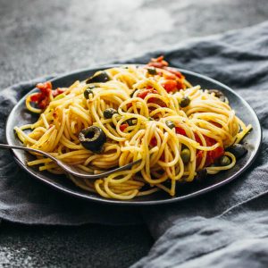 spaghetti puttanesca on a black plate