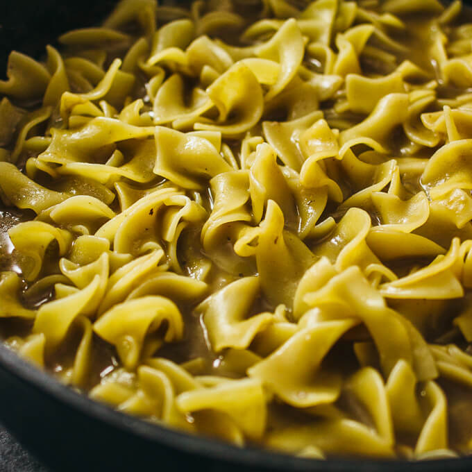 cooking egg noodles in a black pan
