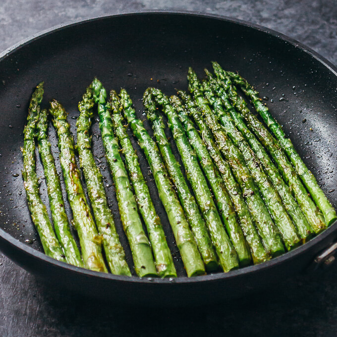 cooking asparagus on a black skillet