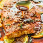 spooning sauce over baked salmon