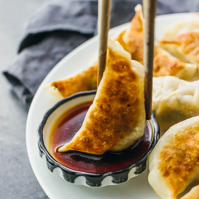 dipping dumplings into soy sauce mixture