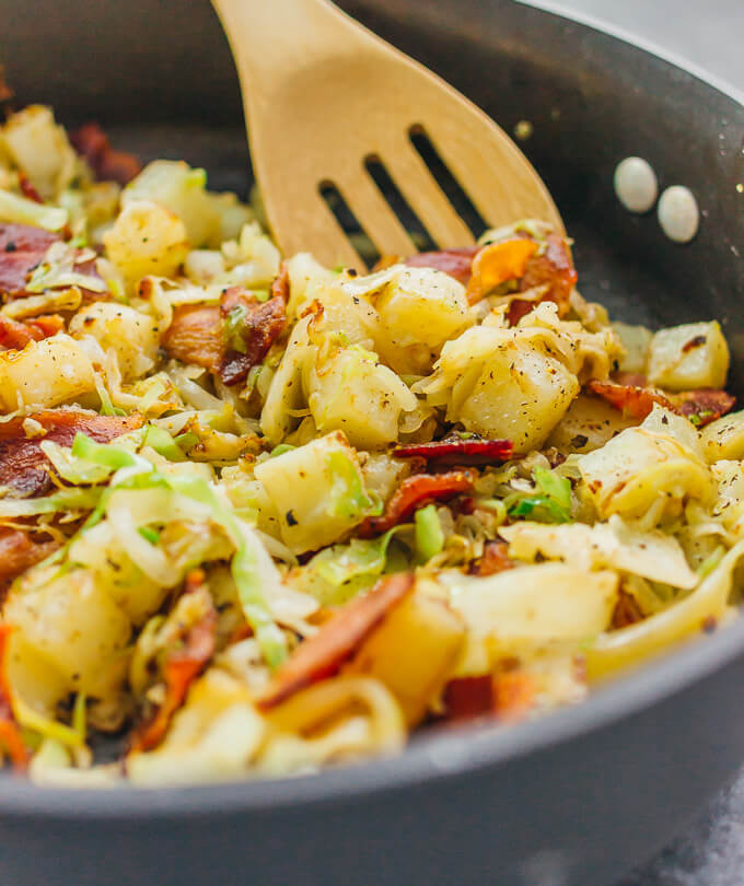stirring cabbage and potatoes in black pan