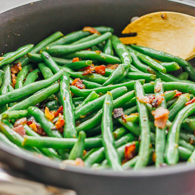 Learn how to cook garlic green beans sauteed with crispy diced bacon and crumbled feta cheese.