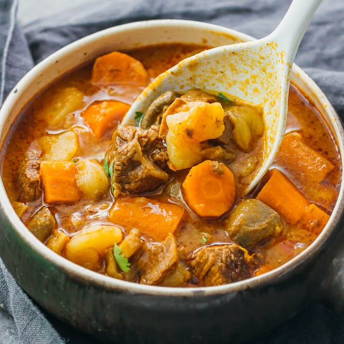 serving beef stew with potatoes into a bowl