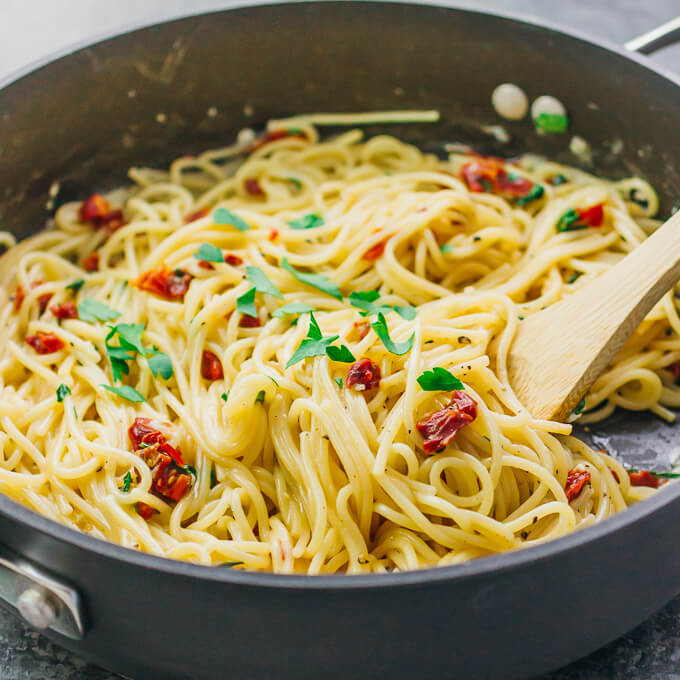 stirring spaghetti in a black pan