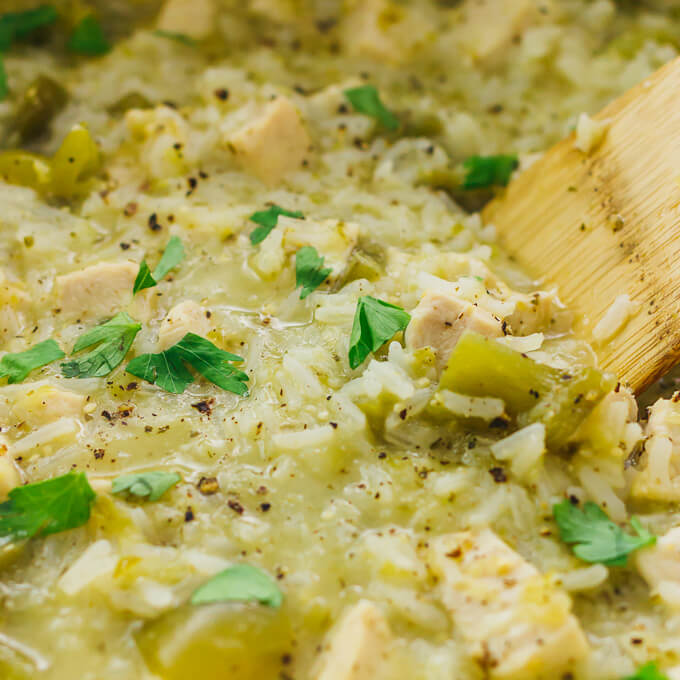 stirring salsa verde chicken and rice in pot