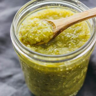 spooning up salsa verde in glass jar