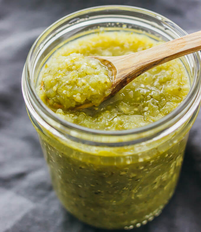 spooning up salsa verde in glass jar
