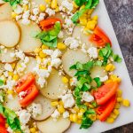 Drizzled with a balsamic horseradish dressing, this flavorful potato salad has sliced red potatoes, tomatoes, corn, feta cheese, and basil leaves.