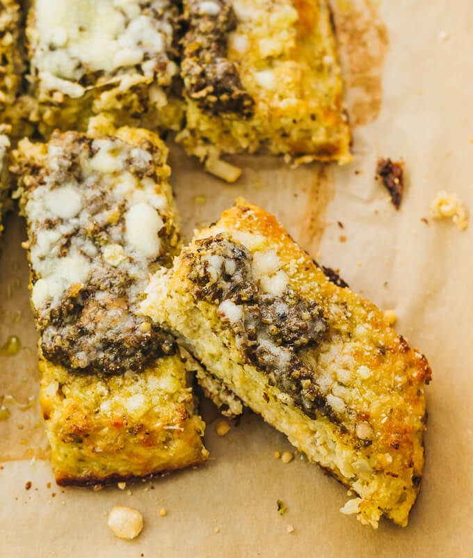 Make this healthy, low carb flatbread recipe using riced cauliflower. It's topped with pesto sauce and grated parmesan cheese.