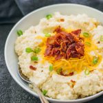 Forget about mashed potatoes -- this cheesy mashed cauliflower is creamy and fluffy, and topped with cheddar cheese and crispy bacon.