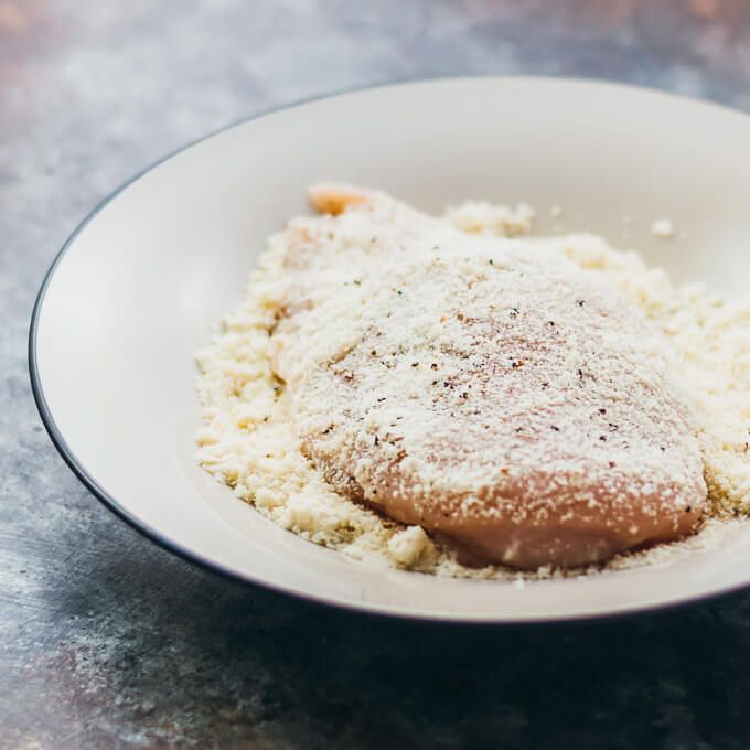 dipping chicken into almond flour