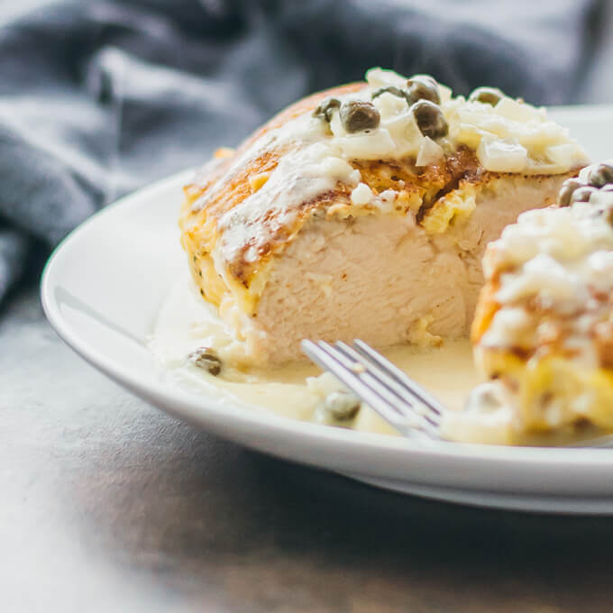 Closeup view of sliced chicken breasts with capers and a creamy lemon sauce