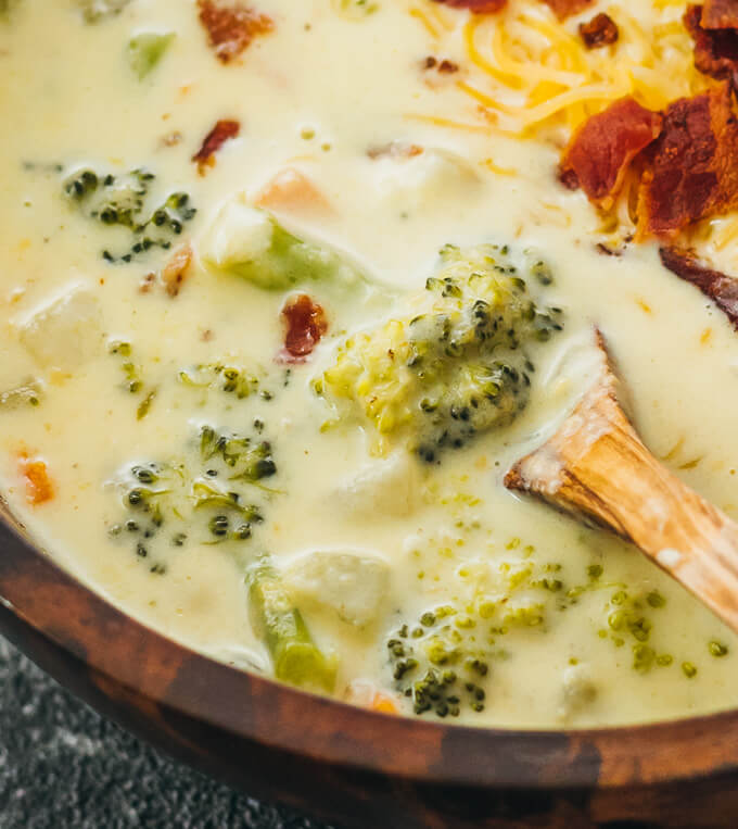 close up view of broccoli cheddar soup in wooden bowl