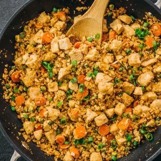 Try this easy cauliflower rice stir fry with chicken and scrambled eggs. Low carb and keto friendly. Overhead shot of rice in the pan.
