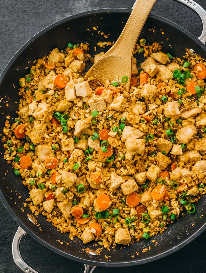 Try this easy cauliflower rice stir fry with chicken and scrambled eggs. Low carb and keto friendly. Overhead shot of rice in the pan.