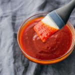 Brush lifting up keto bbq sauce from glass bowl