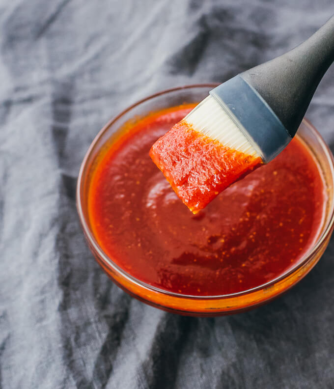 Brush lifting up keto bbq sauce from glass bowl