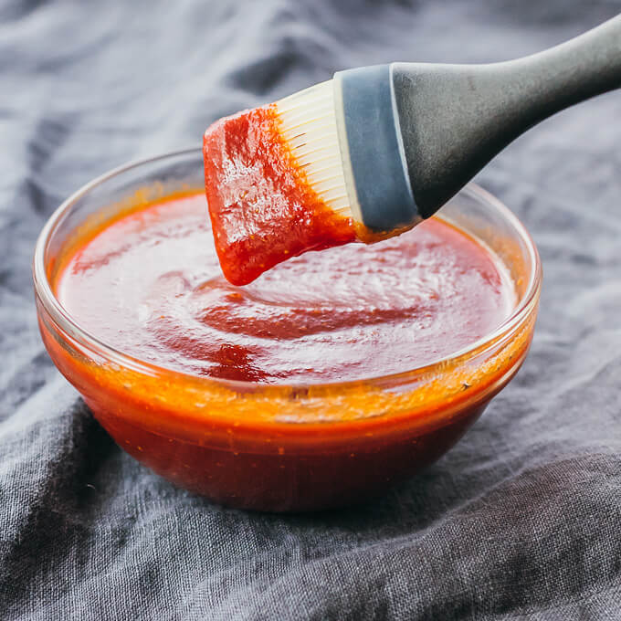 Brush lifting up keto bbq sauce from glass bowl