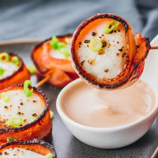 Easy bacon wrapped scallops being dipped in balsamic mayo sauce
