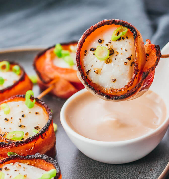 Easy bacon wrapped scallops recipe being dipped in balsamic mayo sauce
