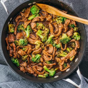Low carb, keto friendly beef and broccoli recipe in an overhead pan shot with wooden spoon