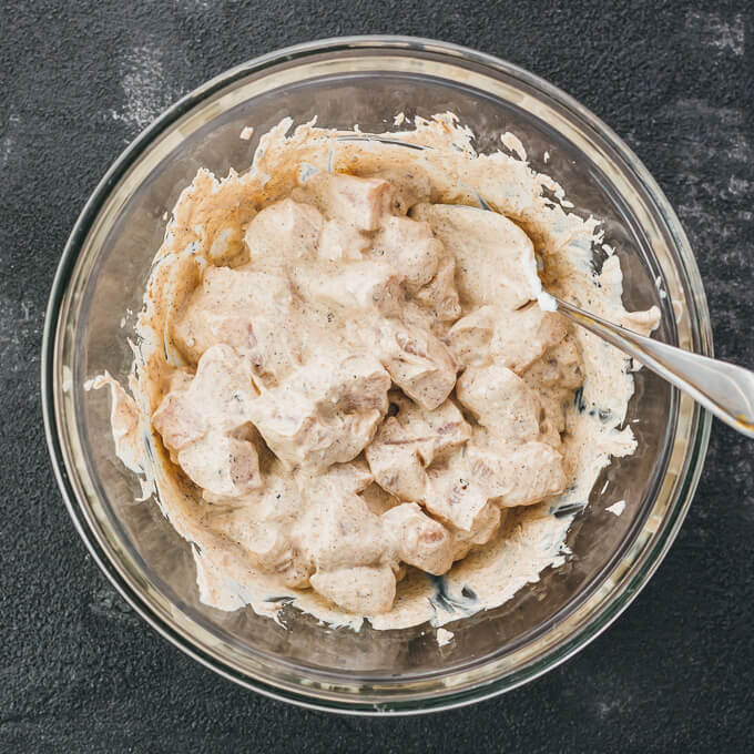 stirring chicken in marinade in glass bowl