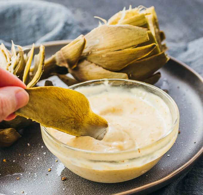 dipping artichoke leaf into mayo dip