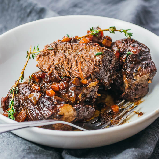 Instant Pot boneless beef short ribs with red wine and balsamic sauce served in a white bowl topped with fresh thyme
