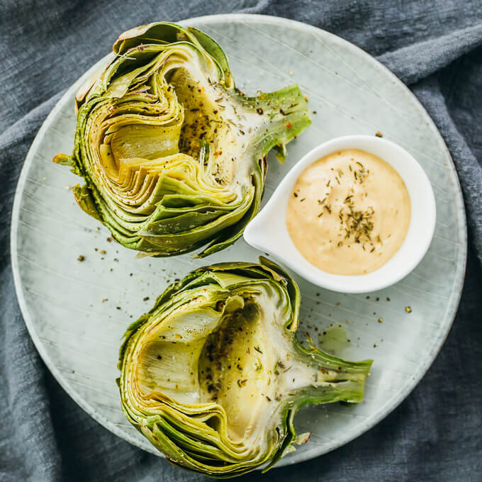 microwaved artichokes served on plate with dip