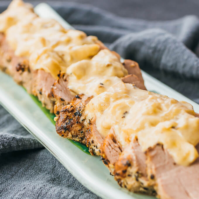 cooked instant pot pork tenderloin drizzled with mustard sauce and onions