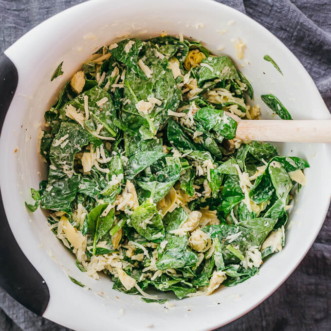 stirring spinach with artichoke and cheese