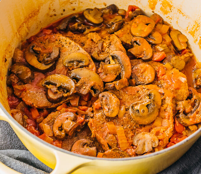 swiss steak cooking in yellow dutch oven