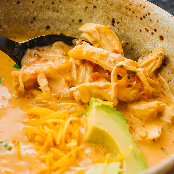 spooning shredded chicken from soup bowl