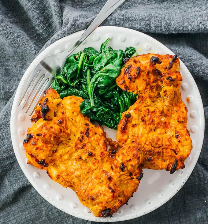 tandoori chicken with spinach served on white plate