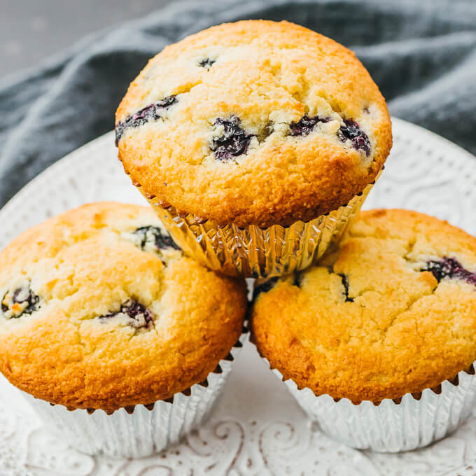 Keto blueberry muffins in foil wrappers on a white plate