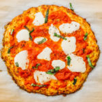 cauliflower crust pizza on parchment paper